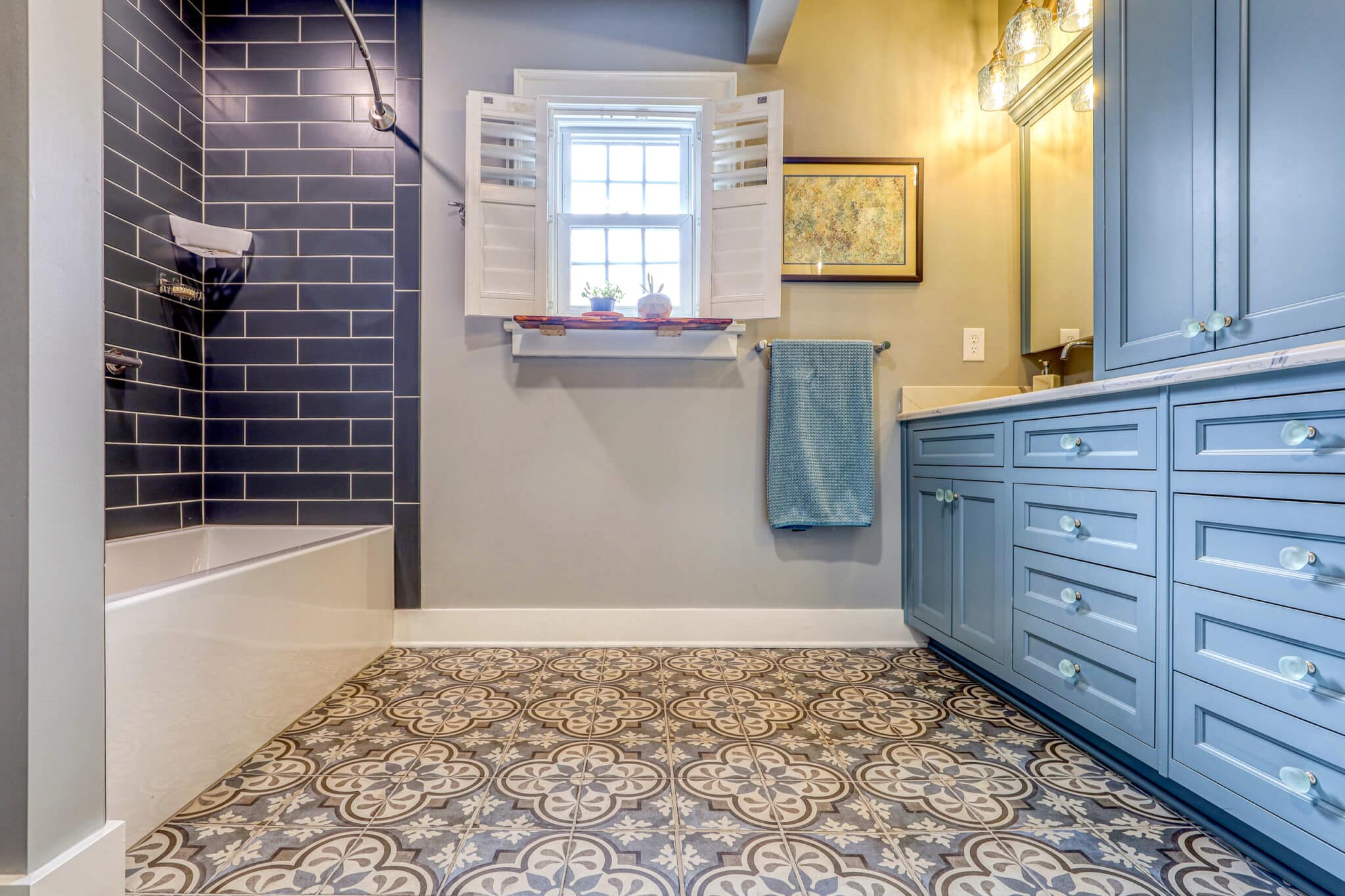 navy subway tile and white tub with Quartetto floor and blue cabinets